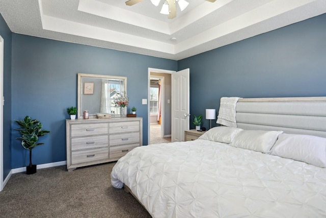 carpeted bedroom featuring a raised ceiling and ceiling fan