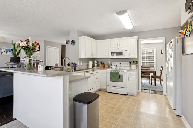 kitchen featuring sink, white appliances, a textured ceiling, white cabinets, and kitchen peninsula