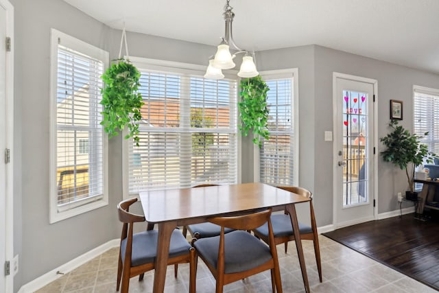 dining room with tile patterned flooring, a healthy amount of sunlight, and an inviting chandelier