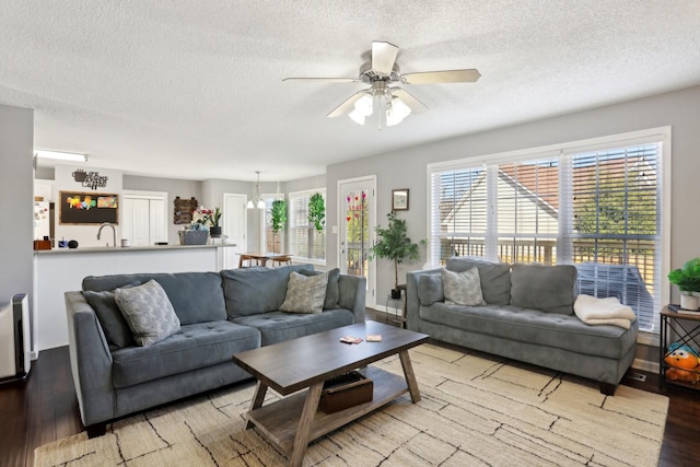 living room with ceiling fan, a textured ceiling, and light hardwood / wood-style floors