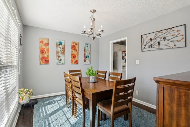 dining space featuring dark hardwood / wood-style floors, an inviting chandelier, and a textured ceiling