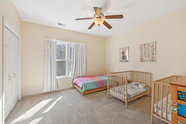 bedroom featuring light colored carpet, a closet, and ceiling fan