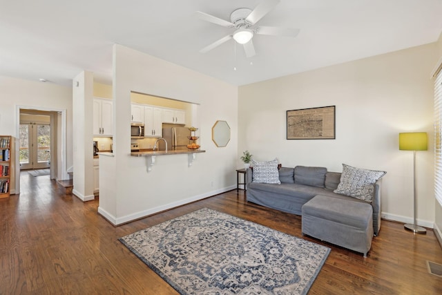 living room featuring dark wood-type flooring, ceiling fan, and sink