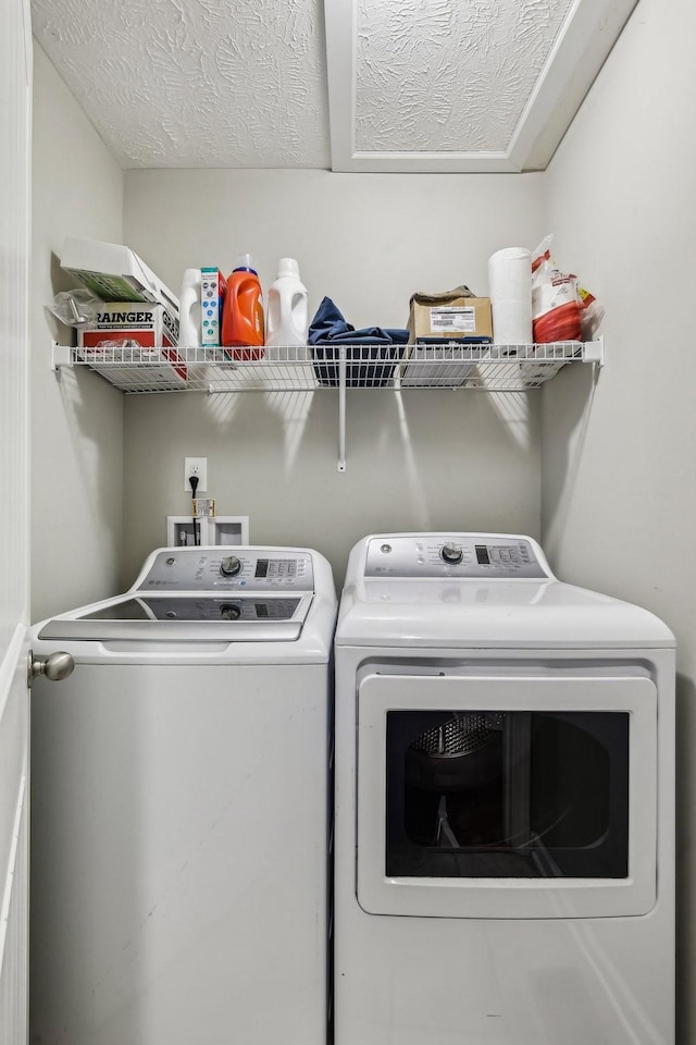 laundry area with washer and clothes dryer and a textured ceiling