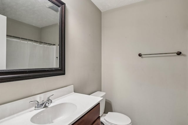 bathroom with vanity, a textured ceiling, and toilet