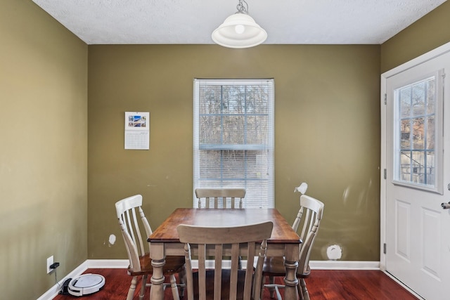 dining space with dark wood-type flooring and a textured ceiling