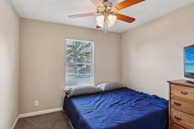 bedroom with ceiling fan, a textured ceiling, and dark carpet