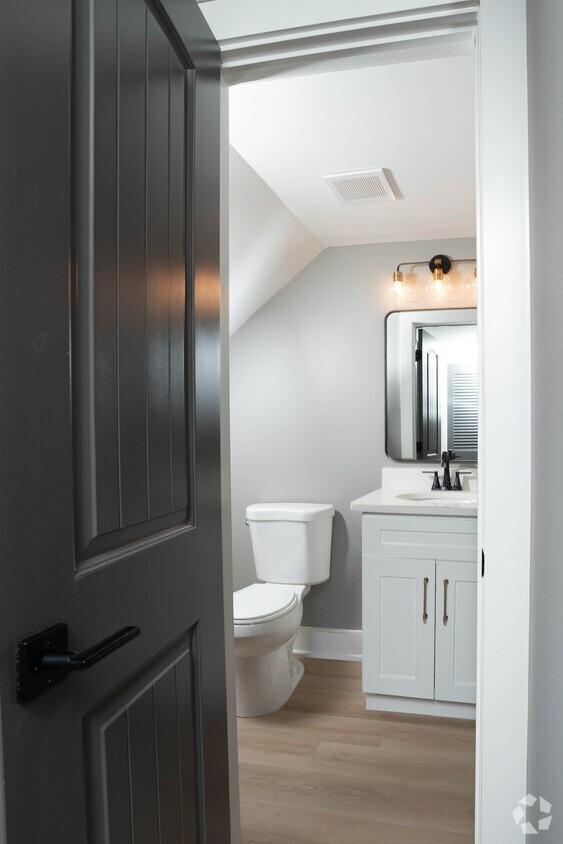 bathroom with lofted ceiling, toilet, hardwood / wood-style floors, and vanity