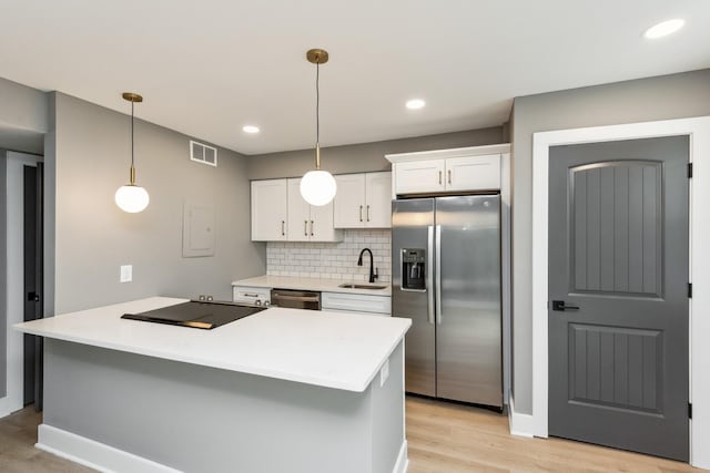 kitchen with sink, appliances with stainless steel finishes, white cabinetry, decorative backsplash, and decorative light fixtures