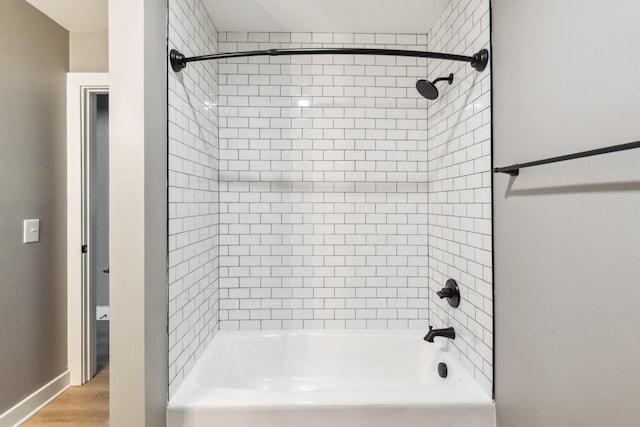 bathroom featuring wood-type flooring and tiled shower / bath