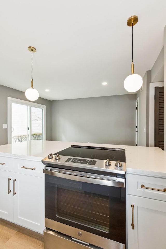 kitchen with pendant lighting, electric range, light hardwood / wood-style flooring, and white cabinets