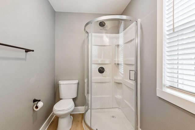 bathroom featuring hardwood / wood-style flooring, an enclosed shower, and toilet