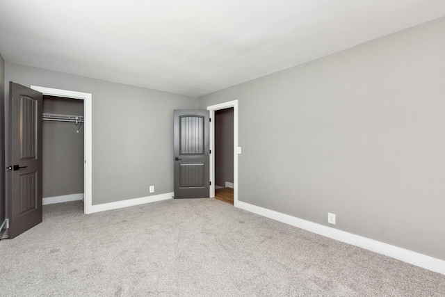 unfurnished bedroom with light colored carpet and a closet