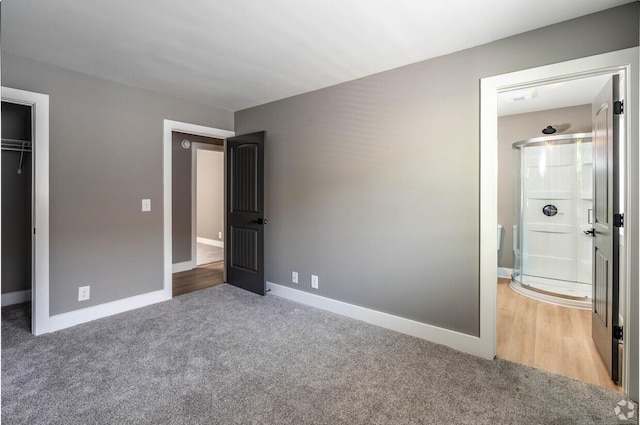 unfurnished bedroom featuring a closet, ensuite bathroom, and carpet flooring