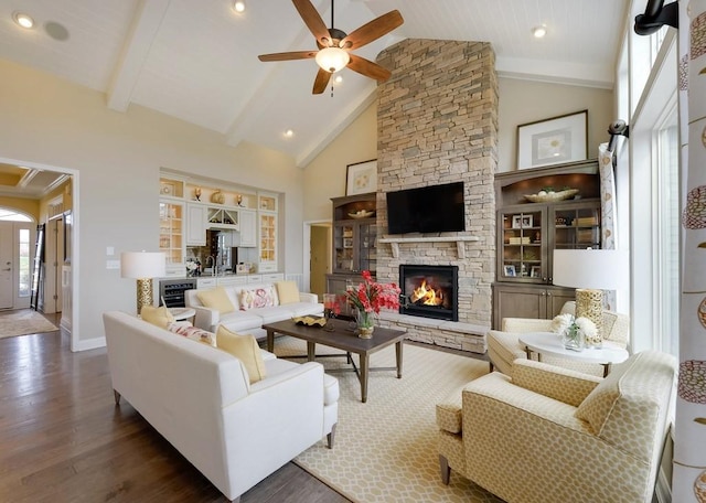 living room with a fireplace, high vaulted ceiling, beamed ceiling, ceiling fan, and dark wood-type flooring