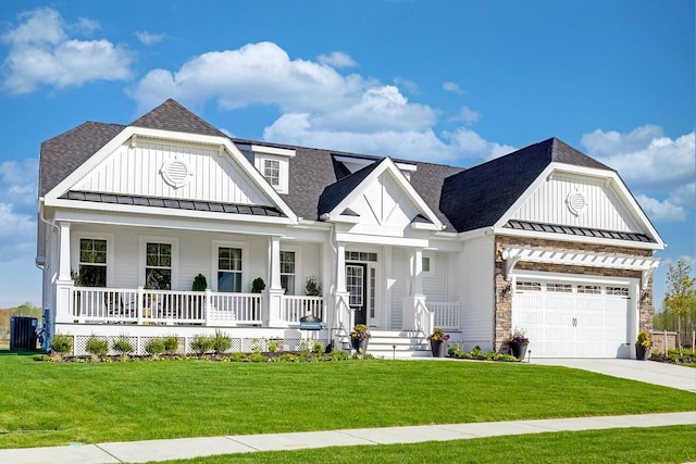 view of front of home featuring a garage, a front yard, central air condition unit, and covered porch