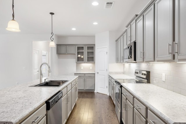 kitchen with pendant lighting, sink, appliances with stainless steel finishes, backsplash, and dark hardwood / wood-style floors