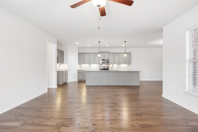 unfurnished living room with ceiling fan, sink, a wealth of natural light, and dark hardwood / wood-style flooring