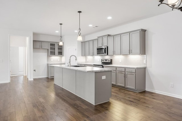 kitchen with sink, gray cabinetry, appliances with stainless steel finishes, an island with sink, and decorative backsplash