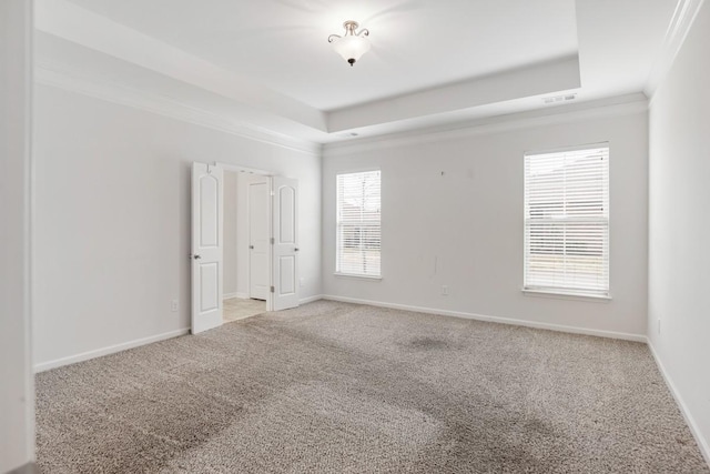 carpeted empty room featuring a raised ceiling and crown molding