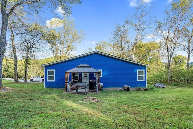 back of property featuring a gazebo and a lawn