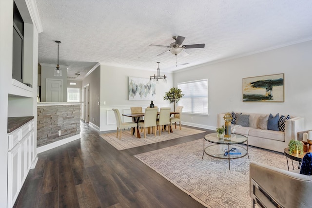 living room featuring dark hardwood / wood-style flooring, ceiling fan with notable chandelier, ornamental molding, and a textured ceiling