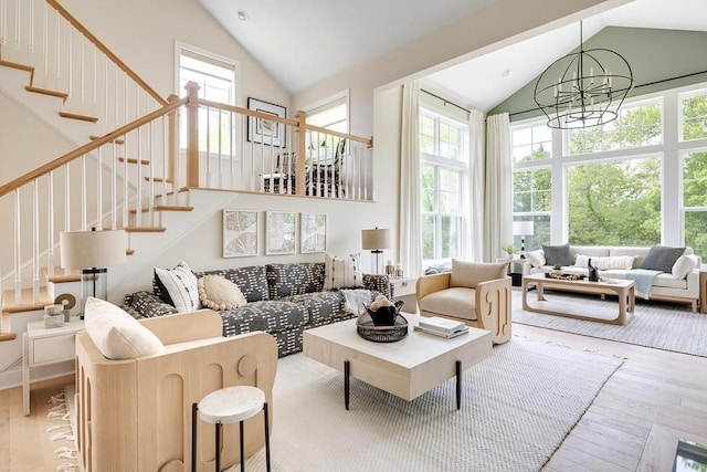 living room featuring high vaulted ceiling, a chandelier, and light wood-type flooring