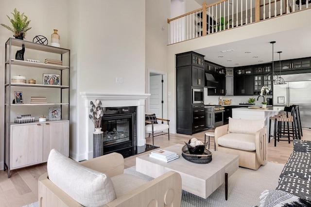 living room featuring sink, light hardwood / wood-style floors, and a towering ceiling