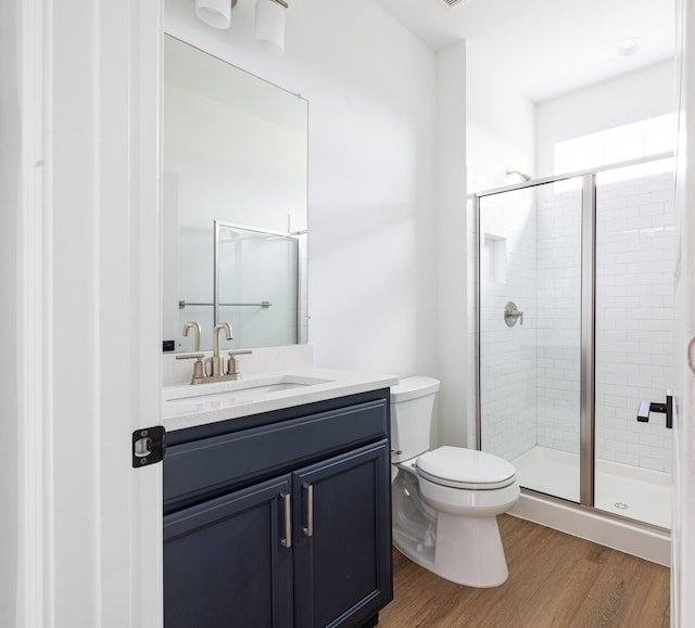 bathroom with vanity, hardwood / wood-style floors, a shower with door, and toilet