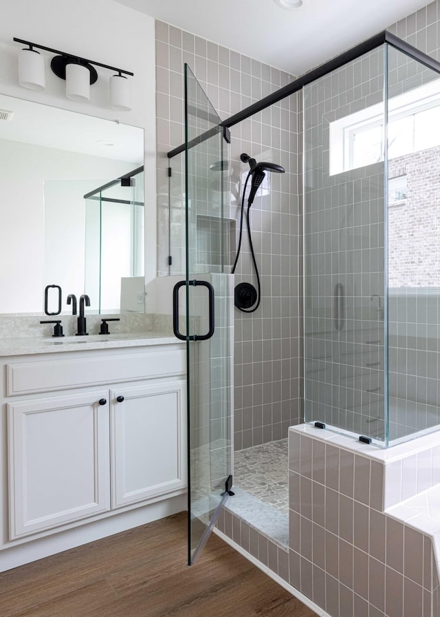 bathroom featuring hardwood / wood-style flooring, vanity, and an enclosed shower