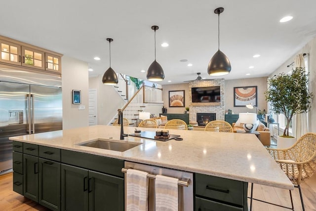 kitchen with stainless steel appliances, an island with sink, and light stone counters