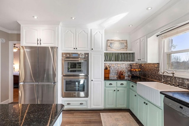 kitchen featuring sink, appliances with stainless steel finishes, white cabinetry, tasteful backsplash, and ornamental molding