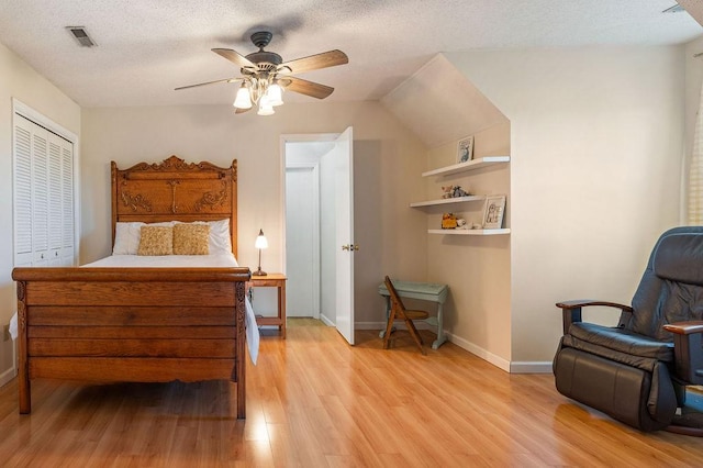 bedroom featuring ceiling fan, a textured ceiling, light wood-type flooring, and a closet