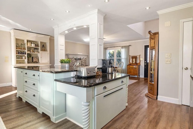 kitchen featuring crown molding, hardwood / wood-style floors, a center island, white cabinets, and dark stone counters