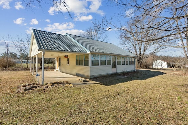 exterior space with a sunroom, a lawn, and a patio area