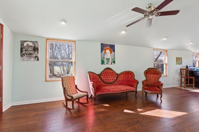 living area with a healthy amount of sunlight, dark hardwood / wood-style flooring, and vaulted ceiling