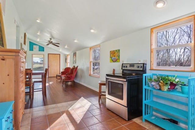 kitchen with stainless steel electric stove, tile patterned floors, a healthy amount of sunlight, and vaulted ceiling