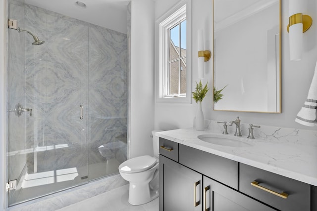 bathroom featuring vanity, a shower with shower door, and toilet