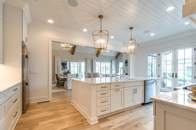 kitchen with sink, appliances with stainless steel finishes, a kitchen island with sink, hanging light fixtures, and white cabinets