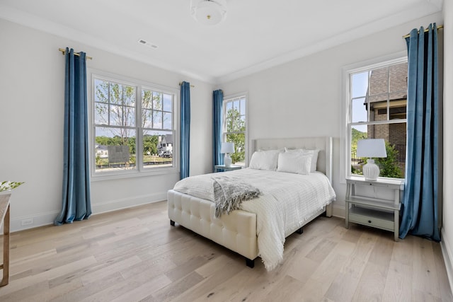 bedroom with ornamental molding and light hardwood / wood-style floors