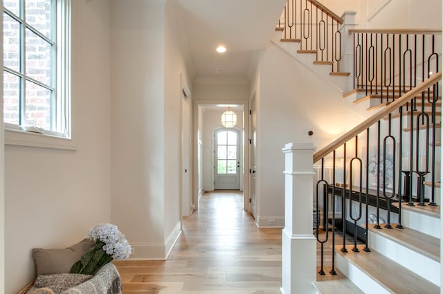 entrance foyer with crown molding and light hardwood / wood-style flooring