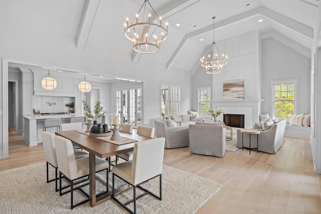 dining area with high vaulted ceiling, a notable chandelier, a fireplace, and light hardwood / wood-style floors