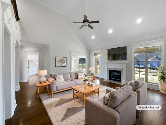 living room with a tiled fireplace, dark wood-type flooring, high vaulted ceiling, and ceiling fan