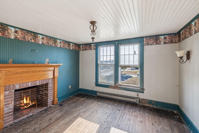 unfurnished living room featuring baseboard heating, dark hardwood / wood-style flooring, and a brick fireplace