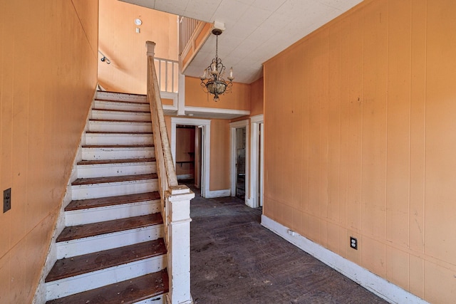 stairway with a notable chandelier and wood walls