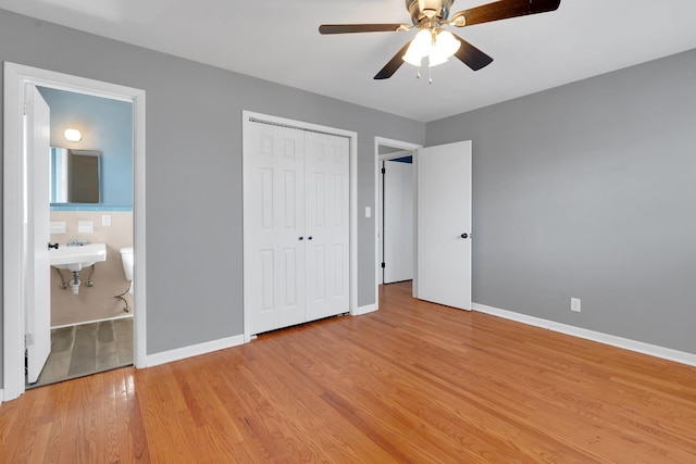 unfurnished bedroom featuring sink, ensuite bath, ceiling fan, light hardwood / wood-style floors, and a closet