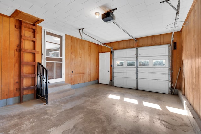 garage with a garage door opener and wood walls