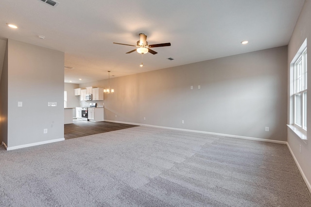 unfurnished living room featuring dark carpet and ceiling fan with notable chandelier