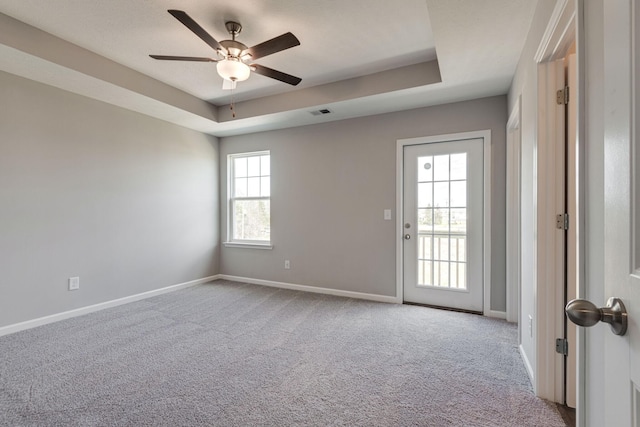 carpeted empty room featuring ceiling fan and a tray ceiling