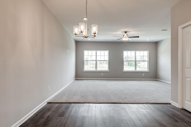 spare room featuring dark hardwood / wood-style flooring, ceiling fan with notable chandelier, and a textured ceiling